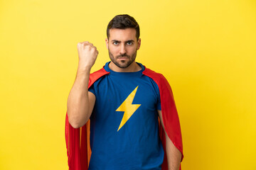Young handsome caucasian man isolated on yellow background in superhero costume © luismolinero