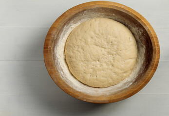 Wooden bowl with yeast dough. Close-up, top view.