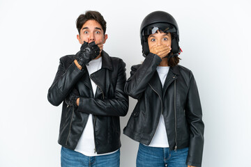Young mixed race couple with a motorcycle helmet isolated on white background covering mouth with hands for saying something inappropriate - obrazy, fototapety, plakaty