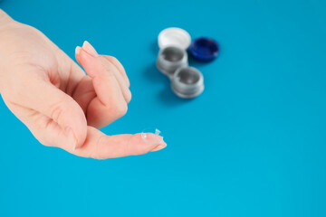 contact lenses care and cleaning,storage,tools and a hand with a lens on a blue background