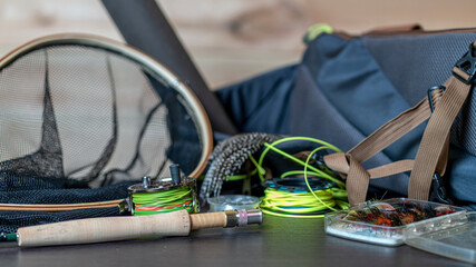 Fly fishing rod, reel and vintage salmon flies in boxes on a distressed black wooden background