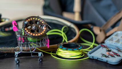 Naklejka premium Photo Fishing rod, fly box, fly fishing reel with line in mini cart. Fly fishing shopping concept.
