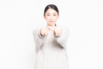 白い背景の前に立ってNGのジェスチャーをする女性