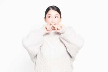 白い背景の前に立ってNGのジェスチャーをする女性
