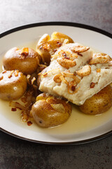 Traditional Portuguese Bacalhau a Lagareiro Oven Cooked Codfish with Potatoes closeup in the plate on the table. Vertical