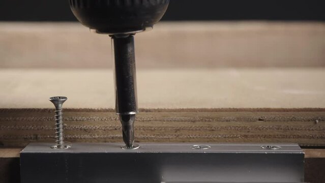 Cordless electric screwdriver unscrews bolts from wood with metal compenent. Slow Motion
