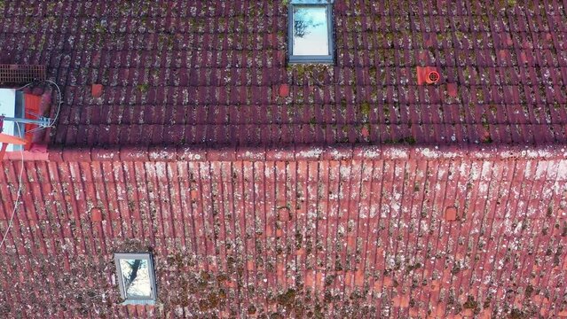 POV from drone ascent over weathered mossy and dirty roof of family house to check condition of roof tiles