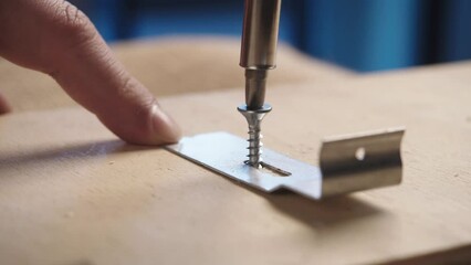 Screwing metal hinge to wood with bolt. Hands of the repairman with a screwdriver. Installation and adjustment, repairment close up shot