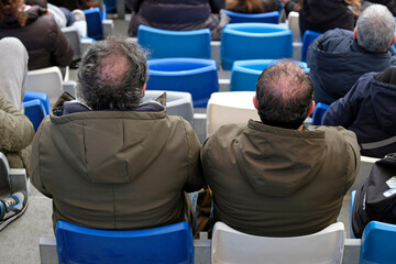 Two men with thin hair watching a football match