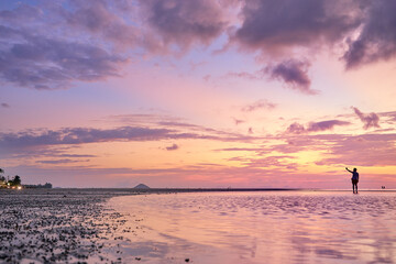 Beautiful sunset on the sea shore with sky reflection in water.