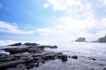 Beautiful balinese landscape. Ocean beach. Ancient hinduism temple Tanah lot on the rock against cloudy sky. Bali Island, Indonesia.