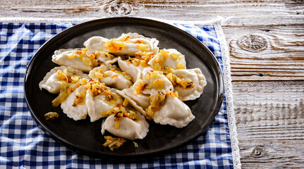 Composition with a plate of classic pierogies with onions