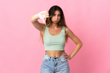Young caucasian woman isolated on pink background showing thumb down with negative expression