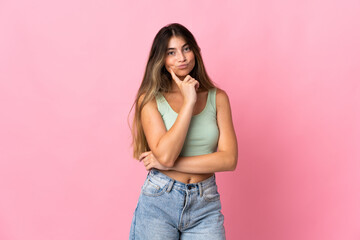 Young caucasian woman isolated on pink background and thinking