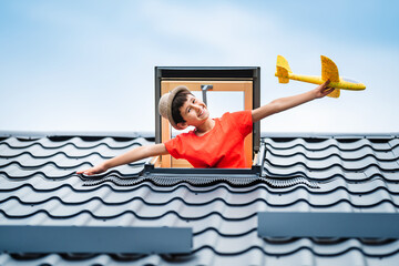 Happy summer vacation. Hello summer concept. Little happy boy playing with toy airplane in an open skylight.