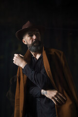 Fototapeta na wymiar Portrait of mature bearded man in coat and hat. Mystical thriller concept. High quality photo