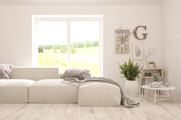 Fototapeta premium Stylish room in white color with sofa and summer landscape in window. Scandinavian interior design. 3D illustration