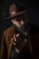 Portrait of mature bearded man in coat and hat. Mystical thriller concept. High quality photo