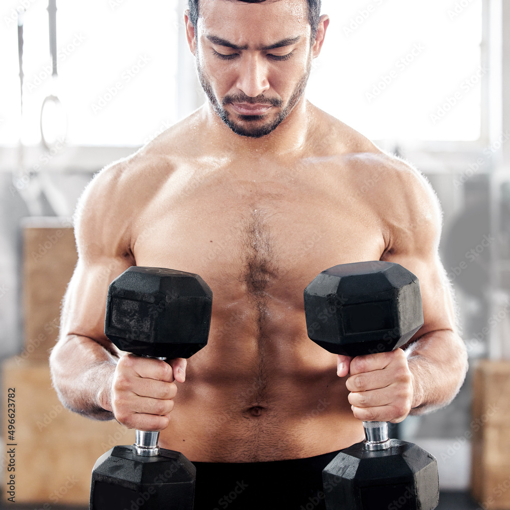 Canvas Prints Mind over matter. Shot of a young man working out with dumbbells in a gym.