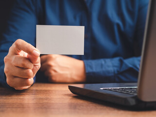 Close-up of hand holding a blank white paper while sitting in the office