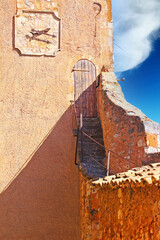 View on ochre natural stone fortress wall tower with clock, steep narrow stairs to ancient wooden...