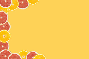 Orange and grapefruit cut in half on an seamless yellow background arranged on the lift side creating the frame, negative copy space
