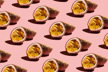 A hard light pattern of a purple passion fruit cut in half on a pink surface