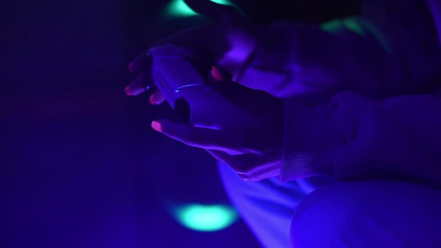 Concept gamer. Nightlife. Leisure. Womans hands holding gamepad. Neon blue light and smoke. Selective focus