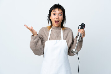 Chef Uruguayan girl using hand blender over isolated white background with surprise facial expression