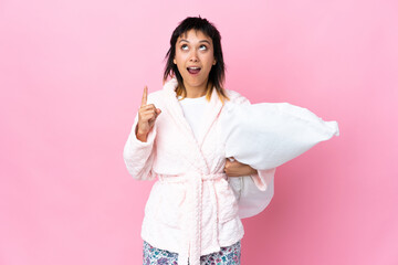Young Uruguayan woman in pajamas over isolated pink background pointing with the index finger a great idea