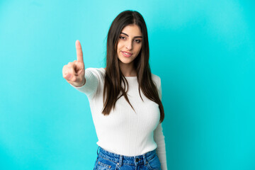 Fototapeta premium Young caucasian woman isolated on blue background showing and lifting a finger