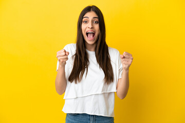 Young caucasian woman isolated on yellow background celebrating a victory in winner position