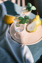 Old-fashioned glasses with fresh cocktails garnished with lemon and mint leaf on terrace on sunny day.