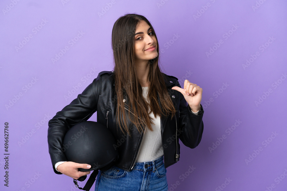 Wall mural Young caucasian woman with a motorcycle helmet isolated on purple background proud and self-satisfied