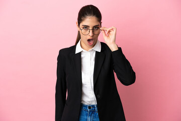 Young caucasian business woman isolated on pink background with glasses and surprised