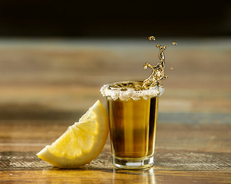 tequila shot drink in a glass decorated with salt with slice of fresh lemon, splash of the drink, frozen movement, pub or night life