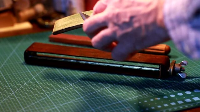 man is sharpening a wood chisel on a leather 