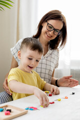 Montessori material. Woman and a boy are studying a puzzle with keys and locks.
