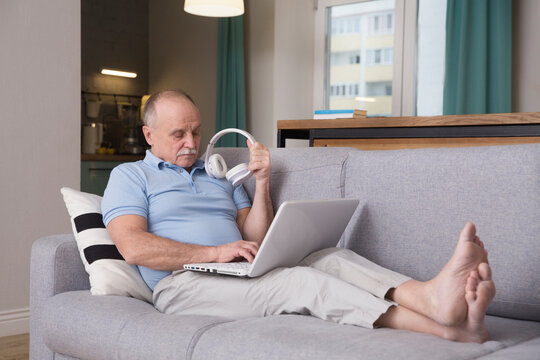 elderly man connecting to the Internet from home. healthy seniors lifestyle. work from home. Senior man using a laptop, in a stylish living room,