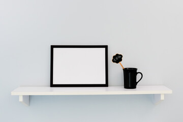 A black horizontal frame, next to a black cup