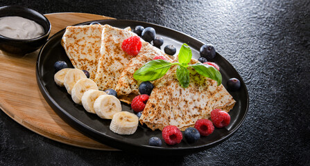 A plate of pancakes with cheese and fruits