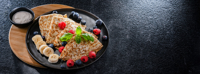A plate of pancakes with cheese and fruits