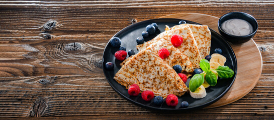A plate of pancakes with cheese and fruits