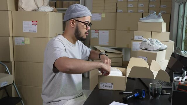 Asian man business owner working, packing the order for shipping to customer. Male entrepreneur packaging box for delivery in store warehouse.