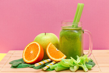 Fresh Green Smoothie of Apple, Celery, Spinach and Orange in Glass Smoothie Jar with Yellow Cocktail Straw on Wooden Cutting Board. Vegan Detox Drink. Vegetarian Culture. Healthy Eating and Fruit Diet