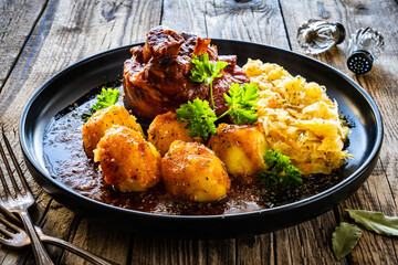 Roast pork knuckle with potatoes and fried cabbage   on wooden table
