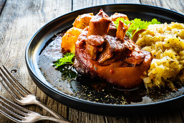 Roast pork knuckle with potatoes and fried cabbage   on wooden table
