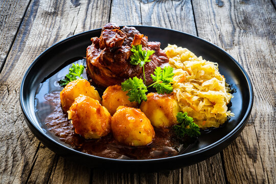 Roast pork knuckle with potatoes and fried cabbage   on wooden table
