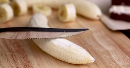 slicing a ripe yellow banana into pieces during cooking