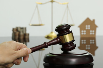 Close-up handle of judge's hammer and scales, house and money, on mirrored floor.
